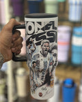 Travel mug with a graphic of a soccer player and text, held by a hand.