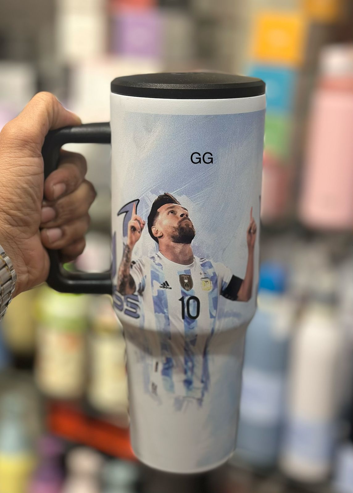 Travel mug with a printed design of a soccer player, held by a person.